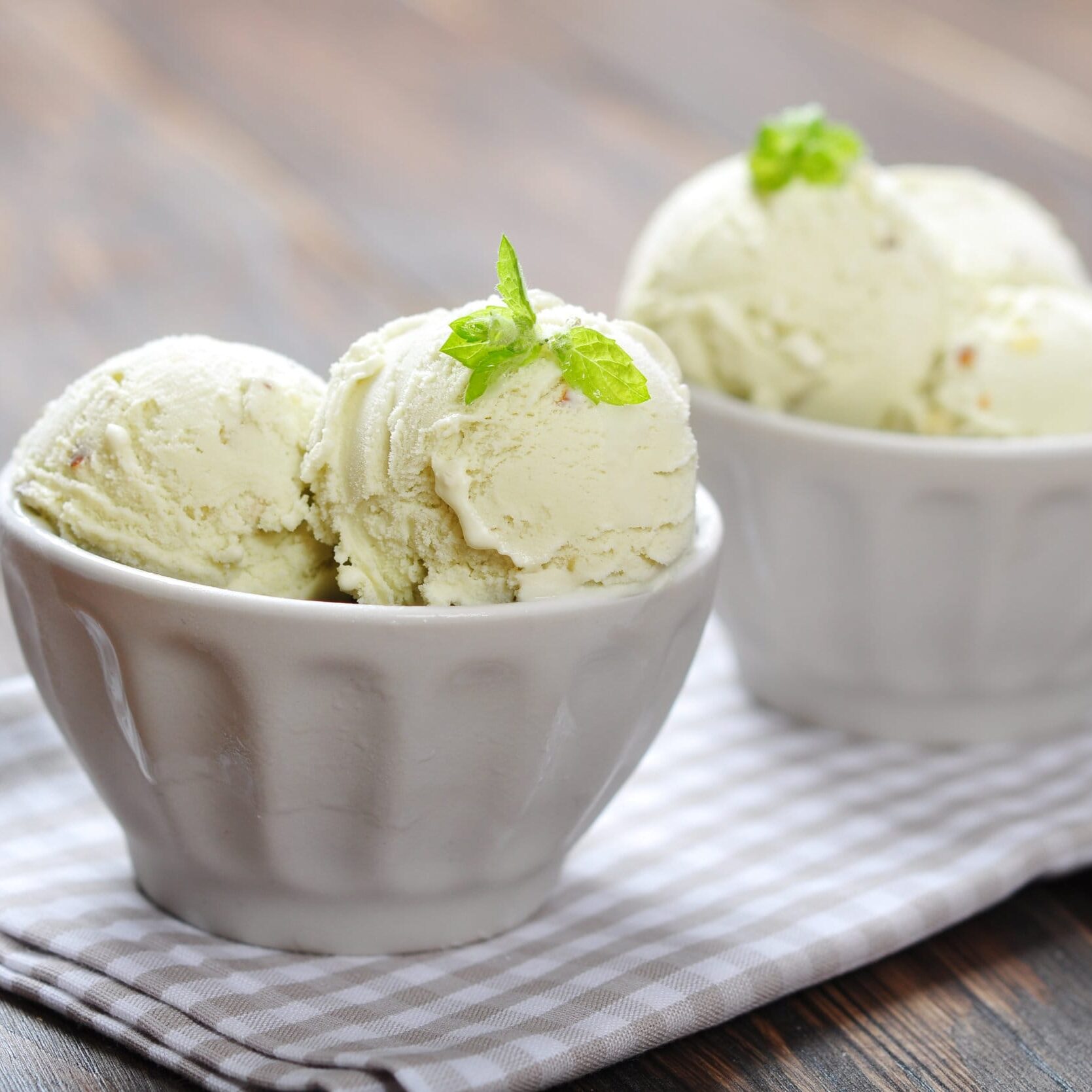 Vanilla ice cream with mint in ceramic bowl on wooden background